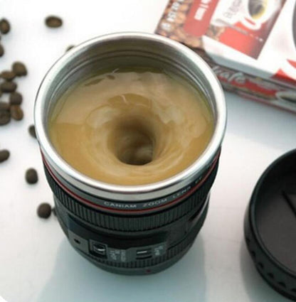Camera lens self stirring mug with coffee swirling inside and coffee beans scattered around.