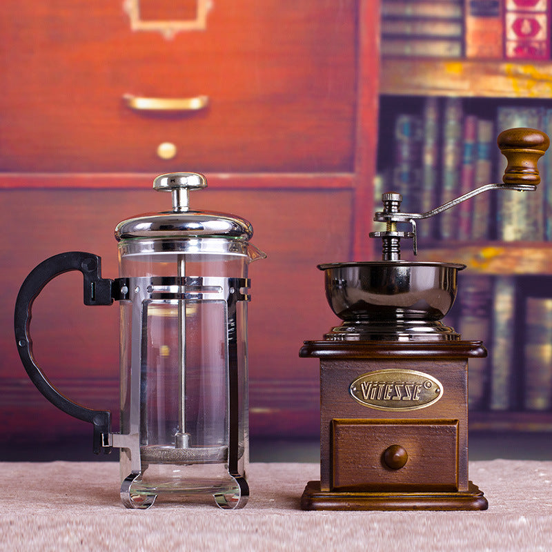 Coffee grinder and French press set displayed on a table, highlighting the artisan quality and traditional brewing method.