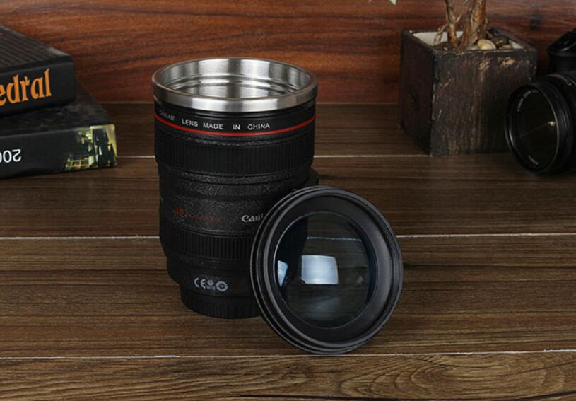 camera lens self stirring mug on a wooden table with a lens cap beside it