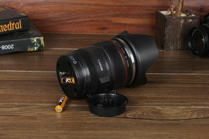 camera lens self stirring mug on wooden table with decorative elements and a battery.