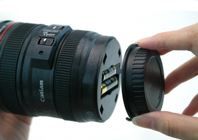 Camera lens self stirring mug showing a person inserting batteries into the bottom, highlighting its unique design and functionality.