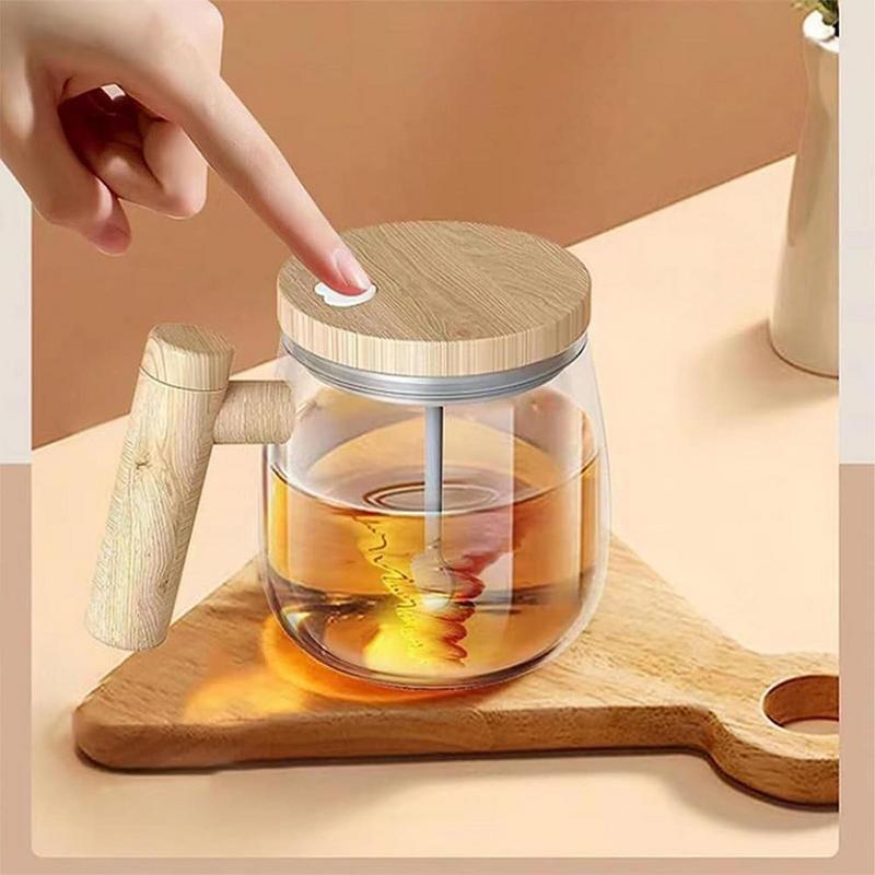 Self stirring coffee mug with a clear glass design and wooden lid, featuring a user pressing the button for effortless mixing.